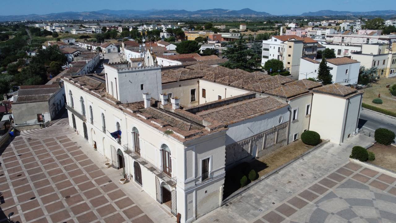 un grande edificio bianco con un'area quadrata con una zona pavimentata